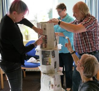 Die Teilnehmer bauen einen Turm aus Zeitungspapier.